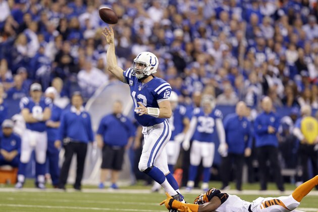 Indianapolis Colts quarterback Andrew Luck (12) throws a 36-yard touchdown pass as he is grabbed by Cincinnati Bengals' Carlos Dunlap, right,  during the second half of an NFL wildcard playoff football game Sunday, Jan. 4, 2015, in Indianapolis. (AP Photo/Michael Conroy)