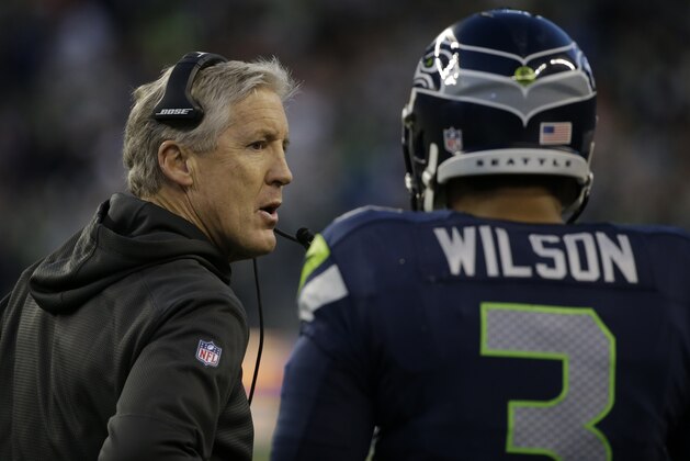 Seattle Seahawks quarterback Russell Wilson, right, talks with Seattle Seahawks head coach Pete Carroll, left, in the second half of an NFL football game against the San Francisco 49ers, Sunday, Dec. 14, 2014, in Seattle. (AP Photo/Elaine Thompson)