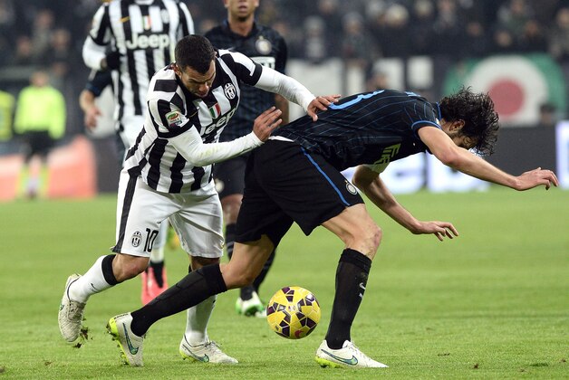 Juventus' Carlos Tevez, left, challenges for the ball with Inter Milan's Andrea Ranocchia, during a Serie A soccer match between Juventus and Inter Milan at the Juventus stadium, in Turin, Italy, Tuesday, Jan. 6, 2015. (AP Photo/ Massimo Pinca)