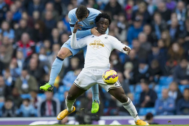 Manchester City's Martin Demichelis, left, gets a hold of Swansea's Wilfried Bony during the English Premier League soccer match between Manchester City and Swansea at the Etihad Stadium, Manchester, England, Saturday Nov. 22, 2014. (AP Photo/Jon Super)