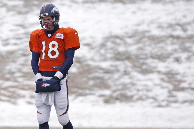 Denver Broncos quarterback Peyton Manning keeps his hands warm in a pouch while waiting to throw the football during practice for the team's NFL divisional playoff game against the Indianapolis Colts Wednesday, Jan. 7, 2015, in Englewood, Colo. (AP Photo/David Zalubowski)