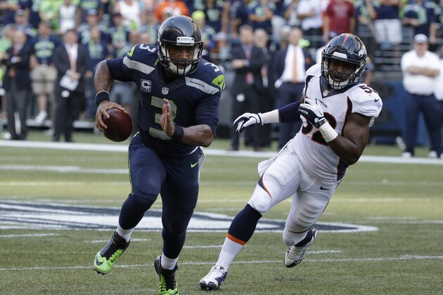 Seattle Seahawks quarterback Russell Wilson (3) scrambles with the football as Denver Broncos outside linebacker Corey Nelson pursues at right, in the second half of an NFL football game, Sunday, Sept. 21, 2014, in Seattle. (AP Photo/Elaine Thompson)