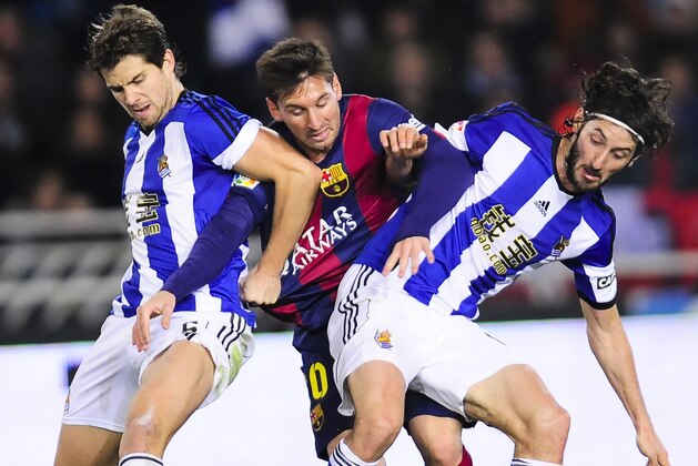 Barcelona's Lionel Messi of Argentina, second left, vies for the ball between Real Rociedad's Inigo Martinez, left,  and Esteban Granero, during their La Liga soccer match against Real Sociedad, at Anoeta stadium in San Sebastian, northern Spain, Sunday, Jan. 4, 2015.  Barcelona lost the match 1-0.(AP Photo/Alvaro Barrientos)