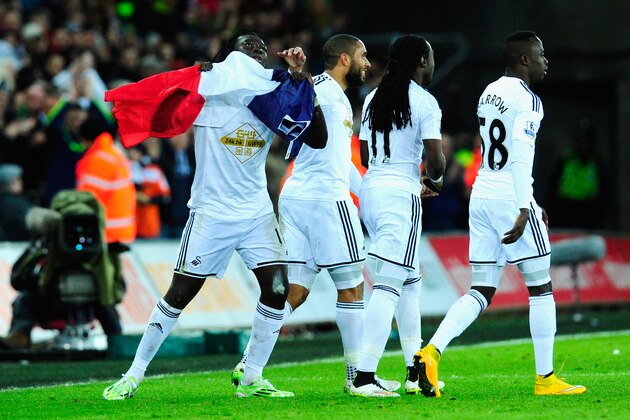 SWANSEA, WALES - JANUARY 10:  Bafetimbi Gomis of Swansea (l) celebrates with team mates and the France national flag after scoring during  the Barclays Premier League match between Swansea City and West Ham United at Liberty Stadium on January 10, 2015 in Swansea, Wales.  (Photo by Stu Forster/Getty Images)