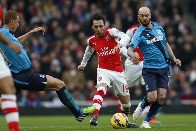 Arsenal's Santi Cazorla, center, passes the tackle from Stoke City’s Steve Sidwell, left, during their English Premier League soccer match between Arsenal and Stoke City at the Emirates stadium in London, Sunday, Jan. 11, 2015. (AP Photo/Alastair Grant)