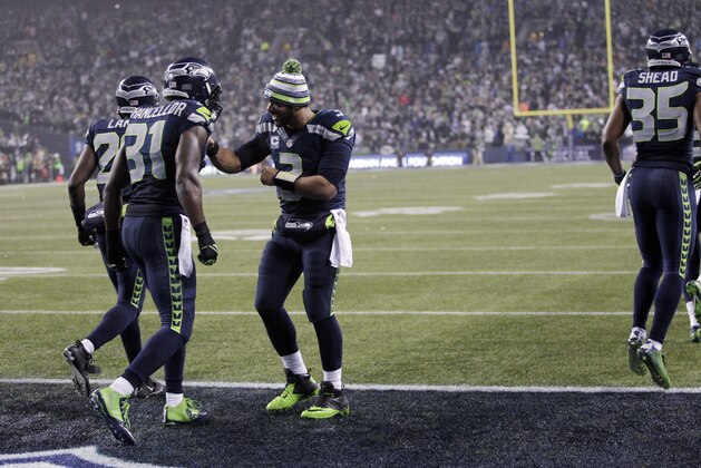 Seattle Seahawks strong safety Kam Chancellor (31) celebrates with quarterback Russell Wilson after scoring on a 90-yard interception return against the Carolina Panthers during the second half of an NFL divisional playoff football game in Seattle, Saturday, Jan. 10, 2015. (AP Photo/John Froschauer)