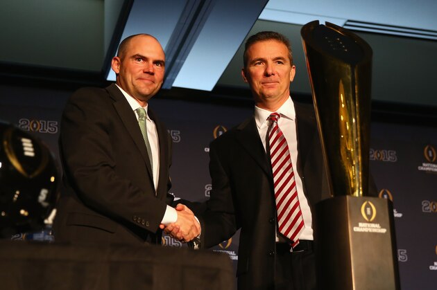 DALLAS, TX - JANUARY 11:  (L-R)  Head Coach Mark Helfrich of the Oregon Ducks and head coach Urban Meyer of the Ohio State Buckeyes greet each other with the College Football Playoff National Championship trophy during a Head Coaches press conference at the Renaissance Dallas Hotel on January 11, 2015 in Dallas, Texas.  (Photo by Ronald Martinez/Getty Images)