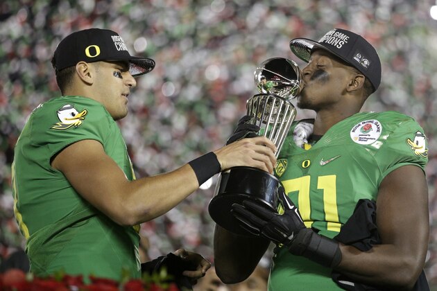 Oregon quarterback Marcus Mariota, left, and linebacker Tony Washington celebrate with the trophy after a 59-20 win over Florida State during the second half of the Rose Bowl NCAA college football playoff semifinal, Thursday, Jan. 1, 2015, in Pasadena, Calif.  (AP Photo/Jae C. Hong)