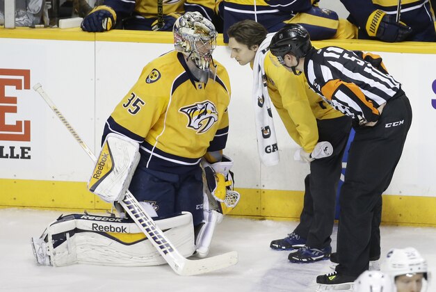 Nashville Predators goalie Pekka Rinne (35), of Finland, is tended to alter a collision in the third period of an NHL hockey game against the Vancouver Canucks Tuesday, Jan. 13, 2015, in Nashville, Tenn. Rinne left the ice and was replaced after the play. (AP Photo/Mark Humphrey)
