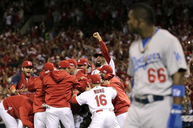 10ThingstoSeeSports - St. Louis Cardinals players celebrate after their 3-2 win over Los Angeles Dodgers in Game 4 of baseball's NL Division Series, Tuesday, Oct. 7, 2014, in St. Louis as Los Angeles Dodgers right fielder Yasiel Puig, right, looks on. (AP Photo/Charles Rex Arbogast, File)