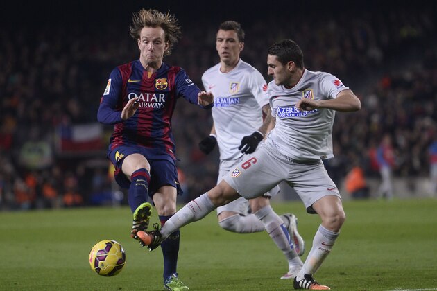 FC Barcelona's Ivan Rakitic, left, duels for the ball against Atletico Madrid's Koke Resurrecion during a Spanish La Liga soccer match at the Camp Nou stadium in Barcelona, Spain, Sunday, Jan. 11, 2015. (AP Photo/Manu Fernandez)