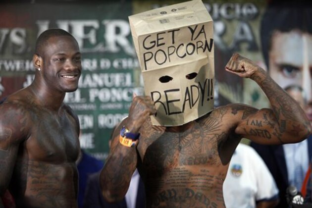 WBC Continental Americas Heavyweight Champion Deontay Wilder, left, and contender Malik Scott, wearing a mask made from a paper bag, pose for photos after the official weigh-in at the Ruben Rodriguez Coliseum in Bayamon, Puerto Rico, Friday, March 14, 2014. Wilder will defend his title against Scott in a Showtime Championship Boxing co-main event Saturday. (AP Photo/Ricardo Arduengo)