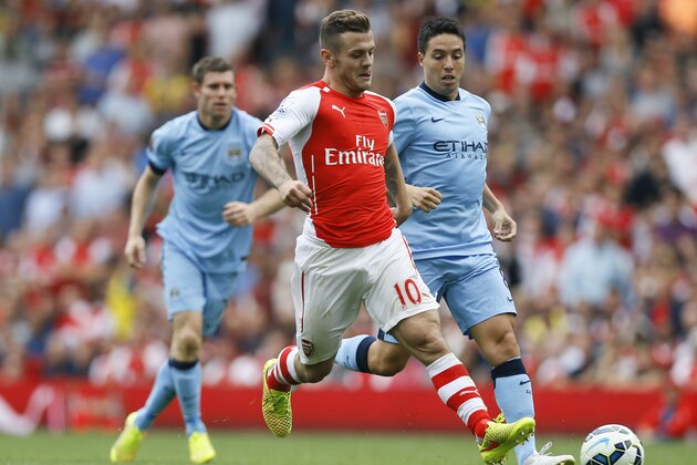 Arsenal's Jack Wilshere, centre, vies for the ball with Manchester City's Samir Nasri, right, during the English Premier League soccer match between Arsenal and Manchester City at Emirates Stadium in London, Saturday, Sept. 13, 2014. (AP Photo/Kirsty Wigglesworth)