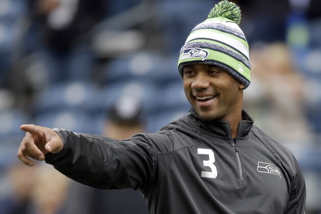 FILE - In this Nov. 2, 2014, file photo, Seattle Seahawks quarterback Russell Wilson smiles as he warms up on the field before an NFL football game against the Oakland Raiders in Seattle. The Seahawks will take on the Green Bay Packers in the NFC Championship game on Sunday, Jan. 18, in Seattle. (AP Photo/Elaine Thompson, File)
