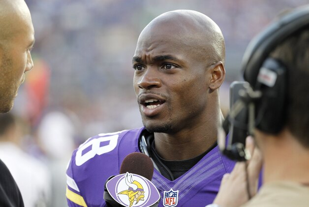 Minnesota Vikings running back Adrian Peterson talks with a sideline commentator during the first half of an NFL football game against the Oakland Raiders in Minneapolis Friday, Aug. 8, 2014. (AP Photo/Ann Heisenfelt)