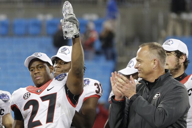 Georgia's Nick Chubb, left, holds up the game MVP trophy as coach Mark Richt, right, applauds after the Belk Bowl NCAA college football game in Charlotte, N.C., Tuesday, Dec. 30, 2014. Georgia defeated Louisville 37-14. (AP Photo/Chuck Burton)