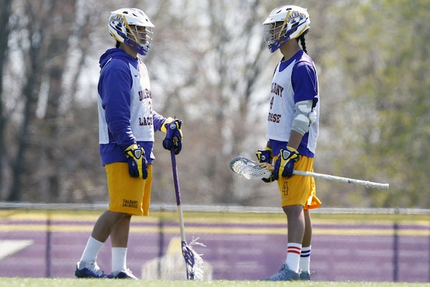 In this photo taken on Monday, April 28, 2014, University at Albany lacrosse players Miles Thompson, left, talks with his brother Lyle Thompson during practice, in Albany, N.Y. A trio of Native American players, Miles, younger brother Lyle, and cousin Ty, have transformed Albany into an offensive juggernaut in Division I men's lacrosse. (AP Photo/Mike Groll)