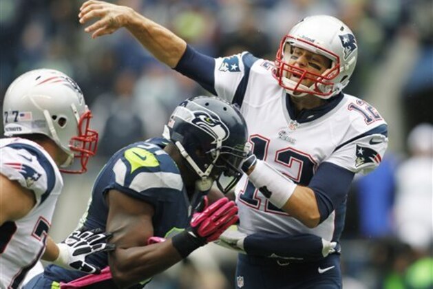 New England Patriots quarterback Tom Brady passes under pressure from Seattle Seahawks' Chris Clemons, center, in the first half of an NFL football game, Sunday, Oct. 14, 2012, in Seattle. (AP Photo/John Froschauer)