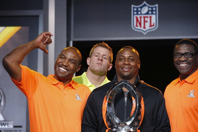 As Troy Vincent, second from right, NFL Executive Vice President of Football Operations, holds the Pro Bowl Trophy, and Michael Irvin, right, NFL Hall of Fame player and Pro Bowl Alumni team captain, the group poses for photographers, Darren Woodson, left, NFL Hall of Fame player and Pro Bowl Alumni co-captain, smiles as he points to Houston Texans Pro Bowl Player J.J. Watt, second from left, who jokingly jumps into the group picture during the Pro Bowl Kickoff news conference Tuesday, Jan. 20, 2015, in Phoenix. (AP Photo/Ross D. Franklin)