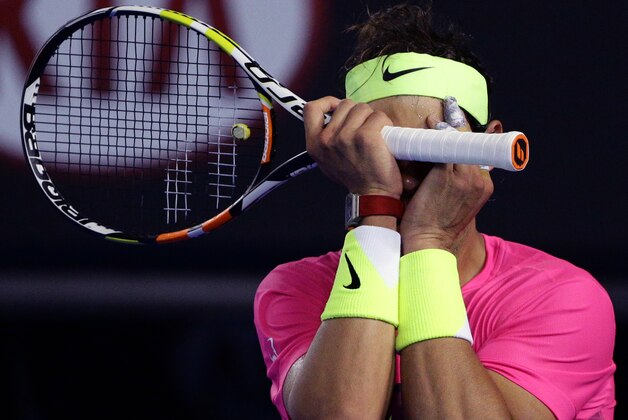 Rafael Nadal of Spain covers his face with a racket as he plays Tim Smyczek of the U.S. during their second round match at the Australian Open tennis championship in Melbourne, Australia, Wednesday, Jan. 21, 2015. (AP Photo/Rob Griffith)
