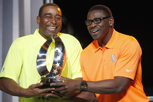 Michael Irvin, right, NFL Hall of Fame member and Pro Bowl Alumni captain, and Cris Carter, left, NFL Hall of Fame member and Pro Bowl Alumni captain, laugh as they playfully try to pull the Pro Bowl trophy away from one another during the Pro Bowl Kickoff news conference Tuesday, Jan. 20, 2015, in Phoenix.  The upcoming NFL Pro Bowl football game will be played on Sunday. (AP Photo/Ross D. Franklin)