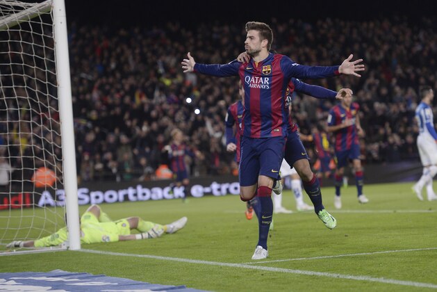FC Barcelona's Gerard Pique, left, reacts after scoring during a Spanish La Liga soccer match against Espanyol at the Camp Nou stadium in Barcelona, Spain, Sunday, Dec. 7, 2014. (AP Photo/Manu Fernandez)