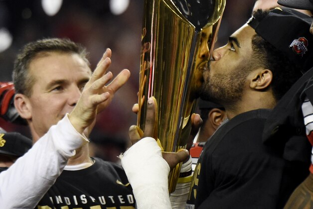 Jan 12, 2015; Arlington, TX, USA; Ohio State Buckeyes running back Ezekiel Elliott (15) kisses the trophy as head coach Urban Meyer hands it to him after their win over the Oregon Ducks in the 2015 CFP National Championship Game at AT&T Stadium. Ohio State won 42-20. Mandatory Credit: Kirby Lee-USA TODAY Sports Jan 12, 2015; Arlington, TX, USA; Ohio State Buckeyes running back Ezekiel Elliott (15) kisses the trophy as head coach Urban Meyer hands it to him after their win over the Oregon Ducks in the 2015 CFP National Championship Game at AT&T Stadium. Ohio State won 42-20. Mandatory Credit: Kirby Lee-USA TODAY Sports