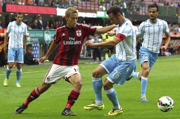 MILAN, ITALY - AUGUST 31:  Keisuke Honda of AC Milan competes for the ball with Stefan Radu of SS Lazio during the Serie A match between AC Milan and SS Lazio at Stadio Giuseppe Meazza on August 31, 2014 in Milan, Italy.  (Photo by Marco Luzzani/Getty Images)