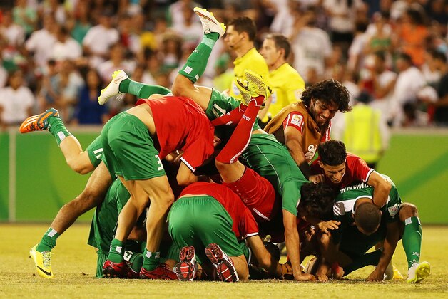 CANBERRA, AUSTRALIA - JANUARY 23:  Iraq players dive on Salam Shakir of Iraq in celebration after he scored the winning penalty during the 2015 Asian Cup match between Iran and Iraq at Canberra Stadium on January 23, 2015 in Canberra, Australia.  (Photo by Stefan Postles/Getty Images)