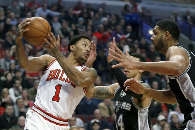Chicago Bulls guard Derrick Rose (1) looks to pass past the defense of San Antonio Spurs guard Danny Green (14) and Tim Duncan during the first half of an NBA basketball game Thursday, Jan. 22, 2015, in Chicago. (AP Photo/Charles Rex Arbogast)