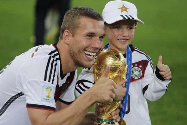 Germany's Lukas Podolski celebrates holding the trophy with his son after the World Cup final soccer match between Germany and Argentina at the Maracana Stadium in Rio de Janeiro, Brazil, Sunday, July 13, 2014. Germany won the match 1-0. (AP Photo/Matthias Schrader)