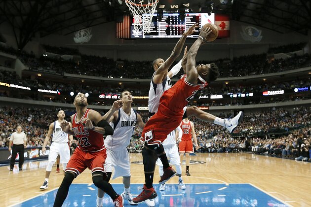 Chicago Bulls guard Jimmy Butler (21) goes up to shoot against Dallas Mavericks' Tyson Chandler, as Dwight Powell, second from left, and the Bulls' Taj Gibson (22) watch in the second half of an NBA basketball game, Friday, Jan. 23, 2015, in Dallas. (AP Photo/Tony Gutierrez)