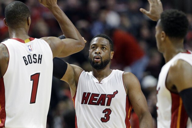 Miami Heat guard Dwyane Wade (3) celebrates with forward Chris Bosh (1) and guard Mario Chalmers, right, after scoring a basket during the second half of an NBA basketball game against the Chicago Bulls in Chicago, Sunday, Jan. 25, 2015. The Heat won 96-84. (AP Photo/Nam Y. Huh)
