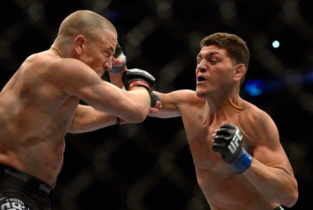 Mar 16, 2013; Montreal, Quebec, CAN;  Nick Diaz (blue) lands a punch on Georges St.Pierre (red) during their Welterweight title bout at UFC 158 at the Bell Centre. Mandatory Credit: Eric Bolte-USA TODAY Sports