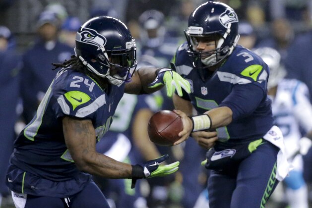 Seattle Seahawks running back Marshawn Lynch, left, takes a handoff from quarterback Russell Wilson against the Carolina Panthers during the first half of an NFL divisional playoff football game in Seattle, Saturday, Jan. 10, 2015. (AP Photo/Ted S. Warren)