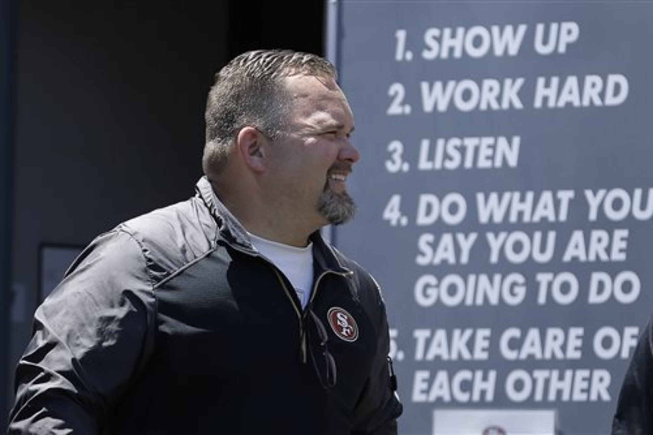 San Francisco 49ers offensive coordinator Greg Roman smiles before speaking to reporters at NFL football minicamp in Santa Clara, Calif., Tuesday, June 17, 2014. (AP Photo/Jeff Chiu)