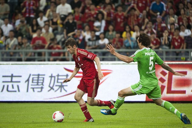 GUANGZHOU, CHINA - JULY 26:  Thomas Mueller (L) of Bayern Muenchen and Pogatetz of VfL Wolfsburg in action during a friendly match as part of the Audi Football Summit 2012 on July 26, 2012 at the Guangdong Olympic Sports Center in Guangzhou, China.  (Photo by Victor Fraile/Getty Images)