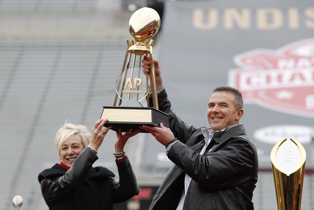 Ohio State coach Urban Meyer, right, and The Associated Press' east regional director Eva Parziale hold up The Associated Press college football national championship trophy during a celebration of the Buckeye's 2014 College Football Playoff national champion  at Ohio Stadium in Columbus, Ohio, Saturday, Jan. 24, 2015. (AP Photo/Paul Vernon)