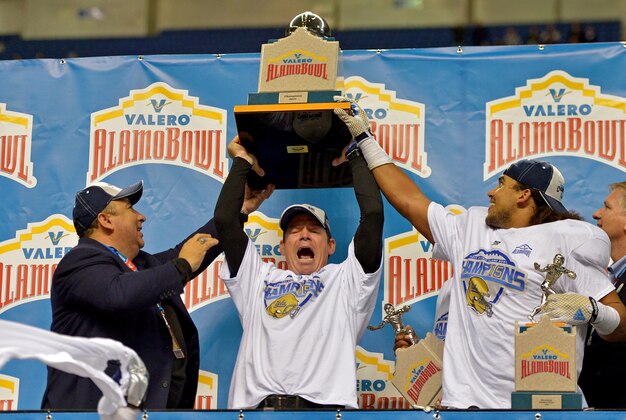 Jan 2, 2015; San Antonio, TX, USA; UCLA Bruins coach Jim Mora (center) hoists the Alamo Bowl trophy assisted by athletic director Dan Guerrero (left) and linebacker Eric Kendricks after the game against the Kansas State Wildcats in the 2015 Alamo Bowl at Alamodome.  UCLA defeated Kansas State 40-35. Mandatory Credit: Kirby Lee-USA TODAY Sports
