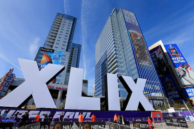 PHOENIX, AZ - JANUARY 28:  People walk past the logo for the upcoming Super Bowl XLIX between the Seattle Seahawks and New England Patriots in an NFL fan on January 28, 2015 in Phoenix, Arizona.  (Photo by Rob Carr/Getty Images)
