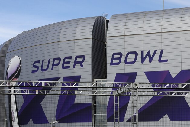 A worker hangs a light on an attraction outside the University of Phoenix Stadium as preparations continue for Super Bowl XLIX Wednesday, Jan. 28, 2015, in Glendale, Ariz. The New England Patriots face the Seattle Seahawks in the game on Sunday, Feb. 1, 2015, in Glendale, Ariz. (AP Photo/Charlie Riedel)
