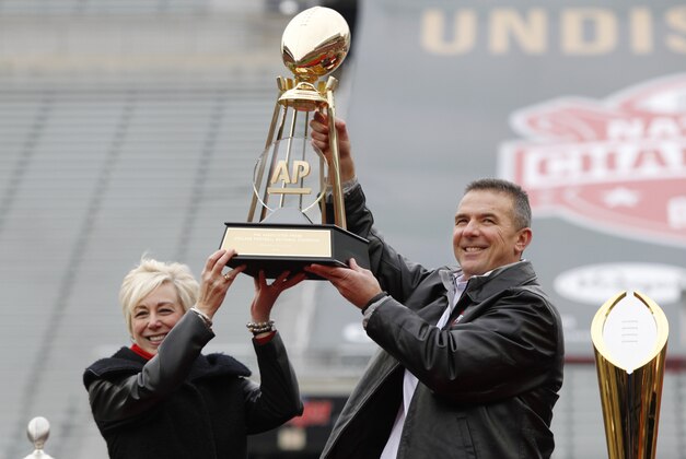 Ohio State coach Urban Meyer, right, and The Associated Press' east regional director Eva Parziale hold up The Associated Press college football national championship trophy during a celebration of the Buckeye's 2014 College Football Playoff national champion  at Ohio Stadium in Columbus, Ohio, Saturday, Jan. 24, 2015. (AP Photo/Paul Vernon)