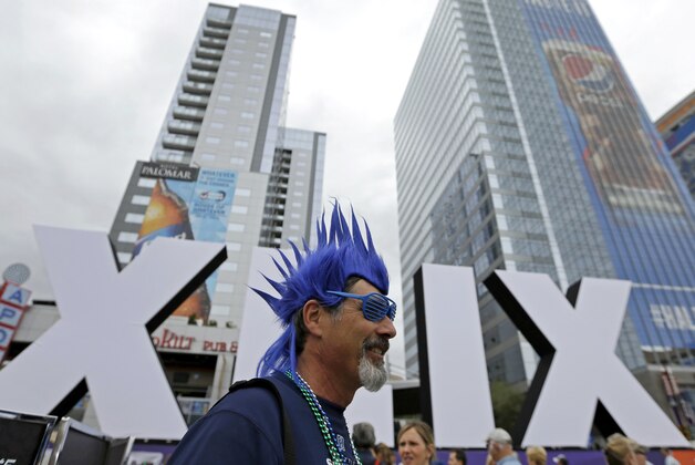 Steve Bronson, from Tempe, Ariz., walks past Roman numerals for the NFL Super Bowl XLIX, Thursday, Jan. 29, 2015, in downtown Phoenix. The New England Patriots face the Seattle Seahawks in Super Bowl XLIX on Sunday in Glendale, Ariz. (AP Photo/Charlie Riedel)