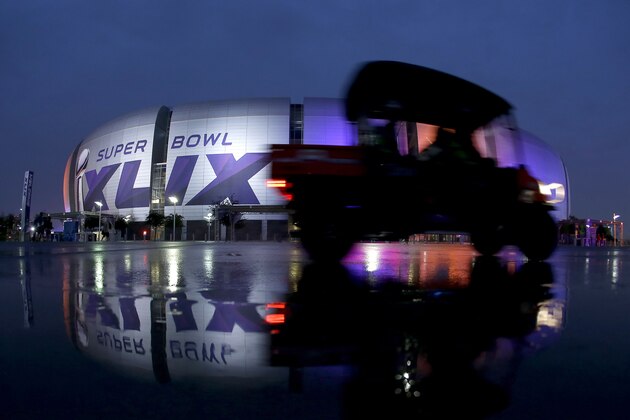Workers drive past the University of Phoenix Stadium Thursday, Jan. 29, 2015, in Glendale, Ariz. The New England Patriots face the Seattle Seahawks in Super Bowl XLIX on Sunday. (AP Photo/Charlie Riedel)