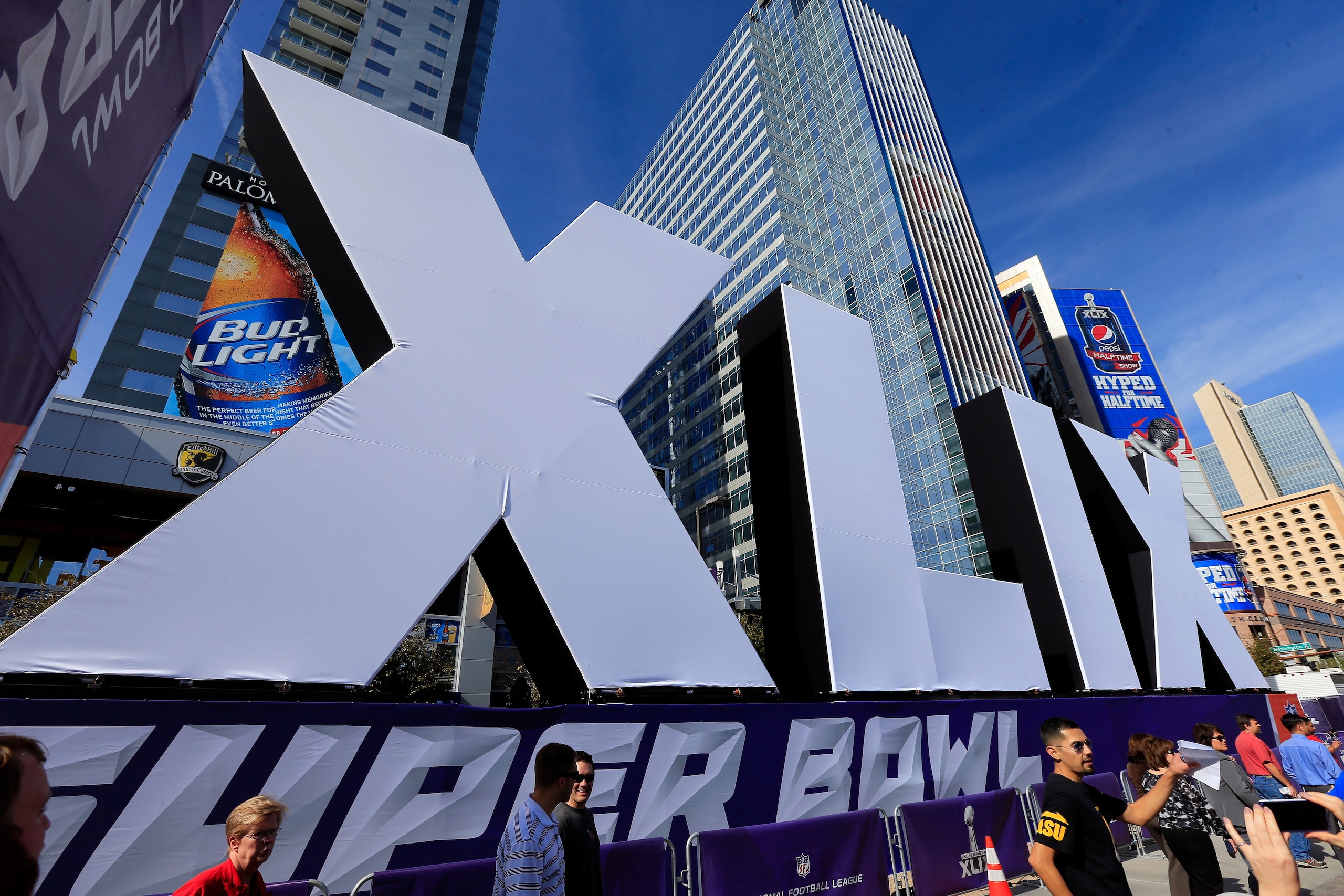 PHOENIX, AZ - JANUARY 28:  People walk past the logo for the upcoming Super Bowl XLIX between the Seattle Seahawks and New England Patriots in an NFL fan on January 28, 2015 in Phoenix, Arizona.  (Photo by Rob Carr/Getty Images)