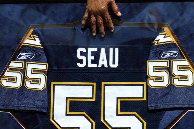 Former San Diego Chargers linebacker Junior Seau's mother, Luisa Seau, touches a replica of Seau's retired No. 55 jersey during a pre-game ceremony before an NFL football game between the Chargers and Tennessee Titans, Sunday, Sept. 16, 2012, in San Diego. The Chargers retired the No. 55 jersey worn by Junior Seau, who committed suicide on May 2. (AP Photo/Denis Poroy)