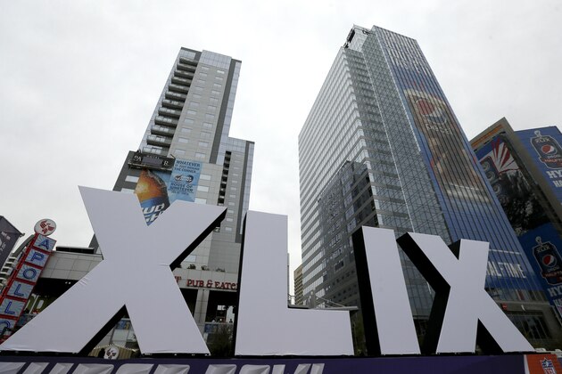 Roman numerals for Super Bowl XLIX stand in front of high-rise buildings Thursday, Jan. 29, 2015, in downtown Phoenix. The New England Patriots face the Seattle Seahawks in Super Bowl XLIX on Sunday in Glendale, Ariz. (AP Photo/Charlie Riedel)
