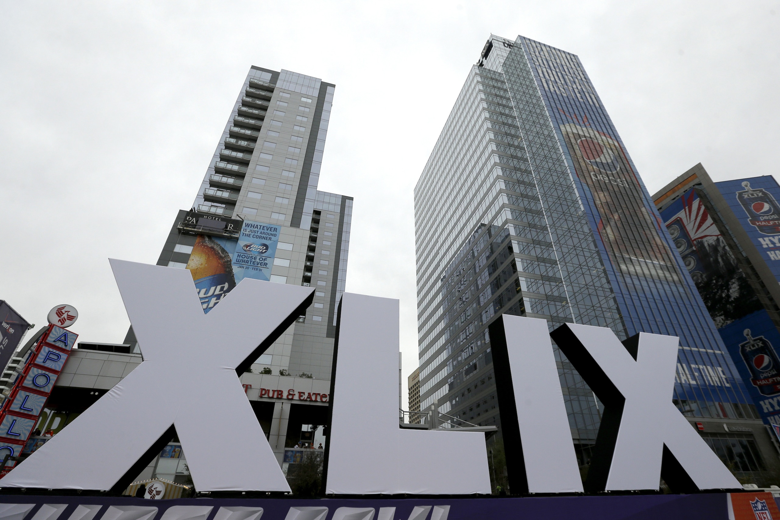 Roman numerals for Super Bowl XLIX stand in front of high-rise buildings Thursday, Jan. 29, 2015, in downtown Phoenix. The New England Patriots face the Seattle Seahawks in Super Bowl XLIX on Sunday in Glendale, Ariz. (AP Photo/Charlie Riedel)