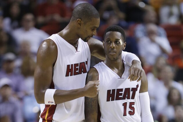 Miami Heat forward Chris Bosh (1) and guard Mario Chalmers (15) chat during the second half of a preseason NBA basketball game against the Houston Rockets, Tuesday, Oct. 21, 2014 in Miami. The Heat defeated the Rockets 90-85. (AP Photo/Wilfredo Lee)