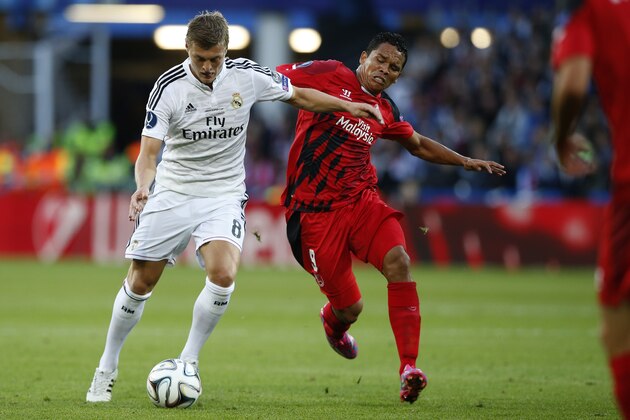 Real Madrid’s Toni Kroos fights for the ball with Sevilla’s Carlos Bacca, left, during the UEFA Super Cup soccer match between Real Madrid and Sevilla in Cardiff City Stadium, in Cardiff, Wales, Tuesday, Aug. 12, 2014. (AP Photo/Alastair Grant)